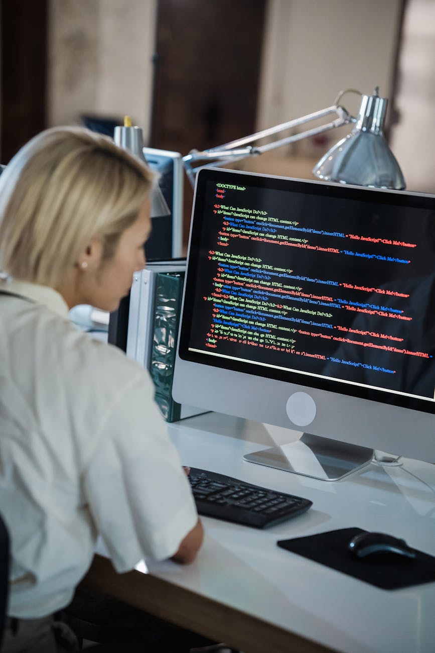 woman with blond hair looking at computer screen with multicoloured code